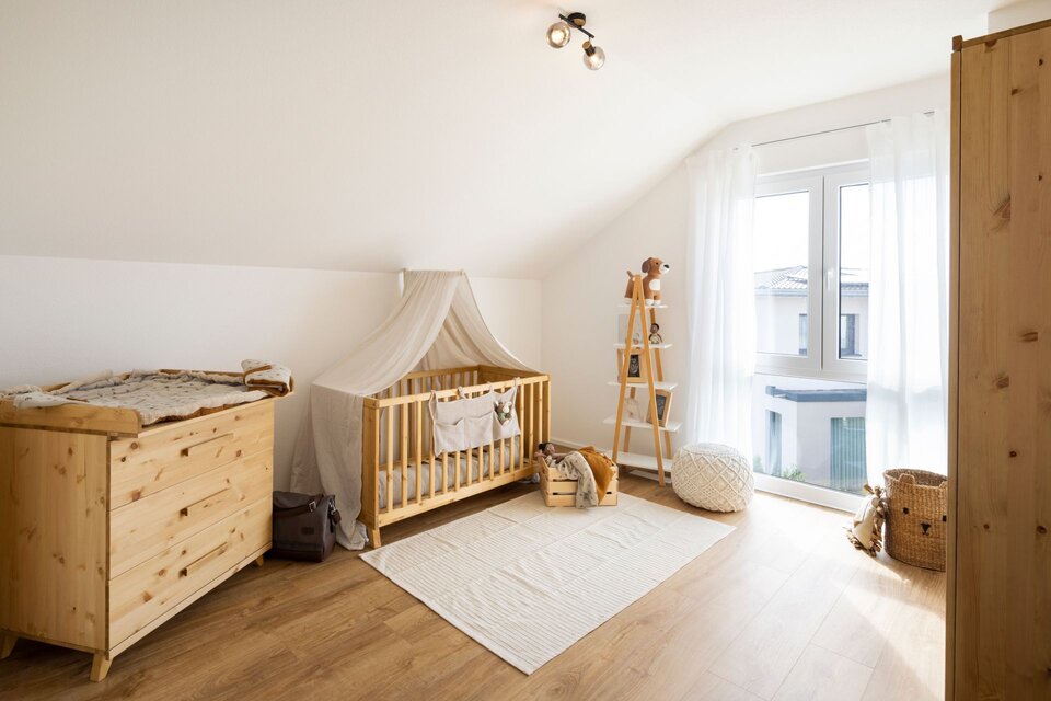 Kinderzimmer mit Holzmöbeln, Baldachin und großem Fenster. Heller Teppich und weiche Farben schaffen eine freundliche Atmosphäre.