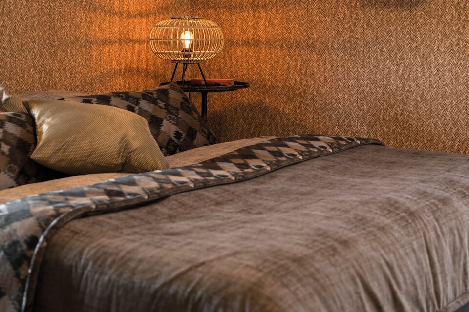 Gemütliches Schlafzimmer mit warmen Brauntönen, dekorativer Tapete und moderner Beleuchtung im Musterhaus UNO 2.0 in Leipzig.