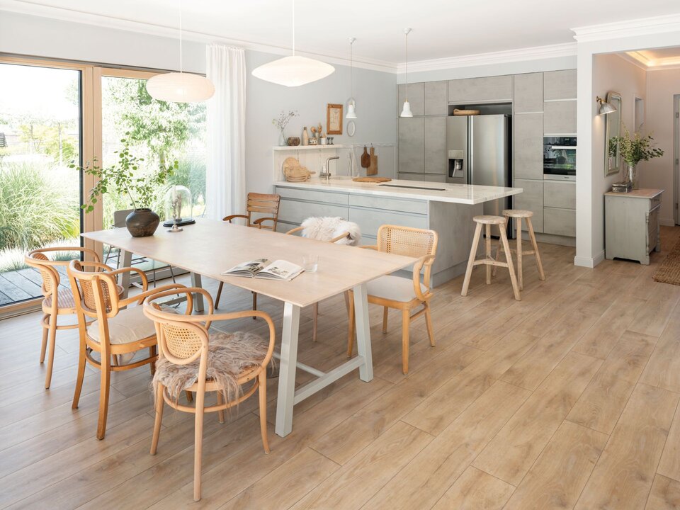 Essbereich mit großem Holztisch, Stühlen aus Naturmaterial, Schiebetür zur Terrasse und offener Verbindung zur Küche.