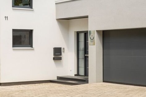 Modernes Einfamilienhaus mit Doppelgarage, heller Fassade und großzügiger Einfahrt