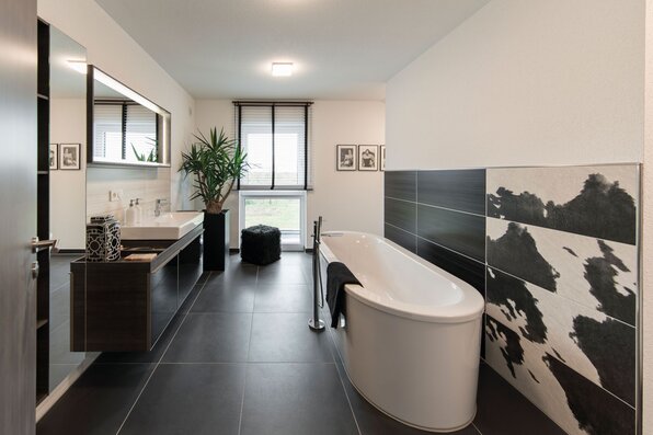 Modernes Badezimmer im FingerHaus MEDLEY 300 B Musterhaus Berlin/Werder mit freistehender Badewanne, Doppelwaschtisch und kontrastreicher Fliesengestaltung.