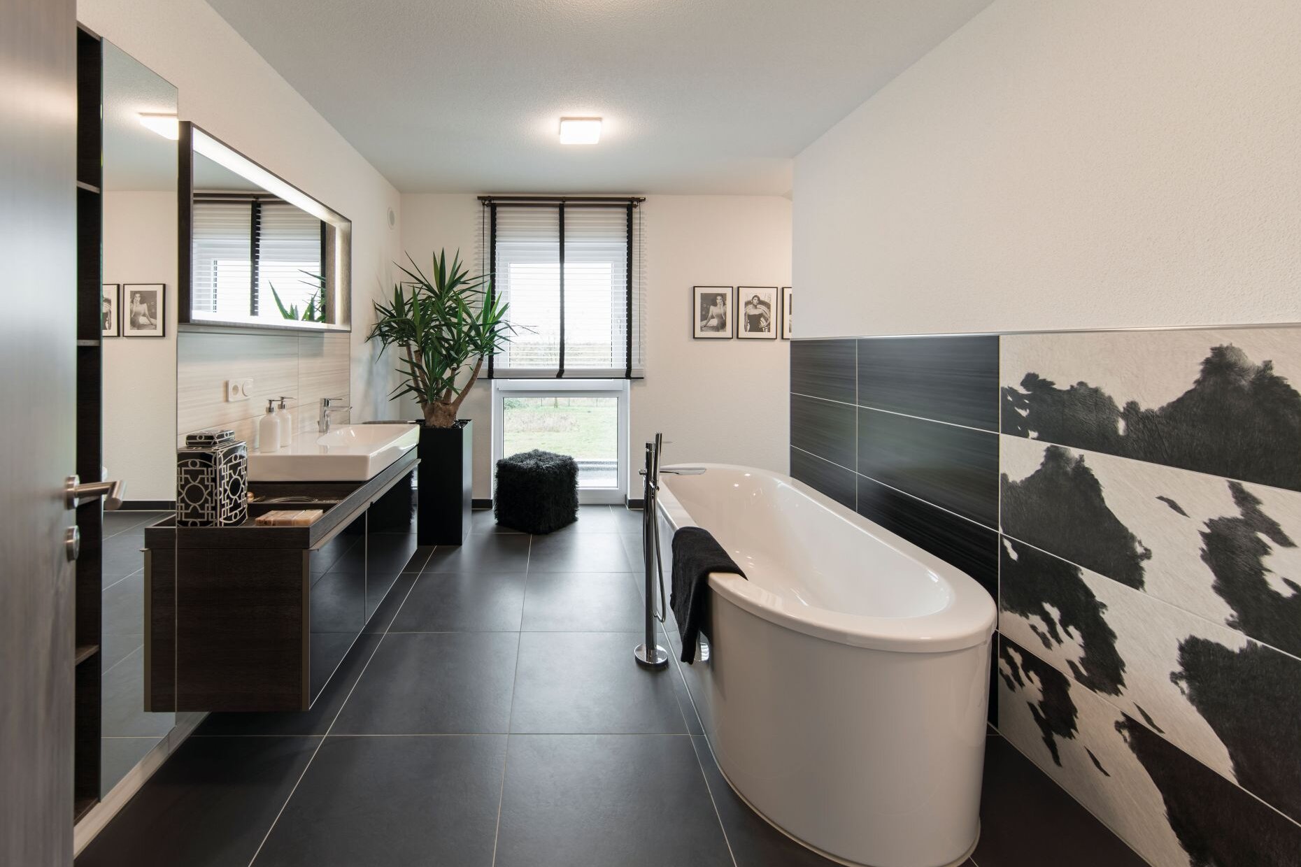 Modernes Badezimmer im FingerHaus MEDLEY 300 B Musterhaus Berlin/Werder mit freistehender Badewanne, Doppelwaschtisch und kontrastreicher Fliesengestaltung.