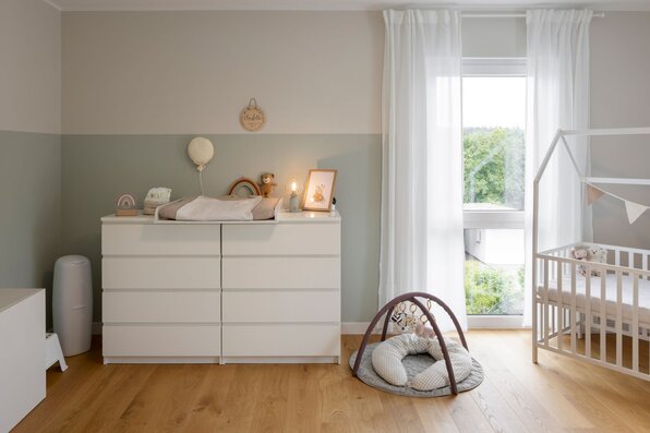 Liebvoll eingerichtetes Babyzimmer mit Wickelkommode, Gitterbett und Spielecke in einem frei geplanten FingerHaus.