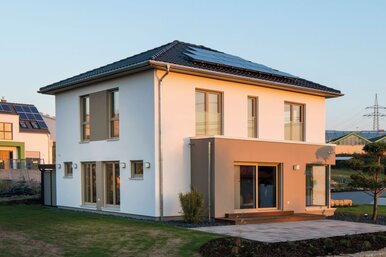 Rückansicht des Musterhauses MEDLEY 300 B in Kassel mit klarer Architektur, großen Fensterflächen und FingerHaus-Flagge im Vordergrund.
