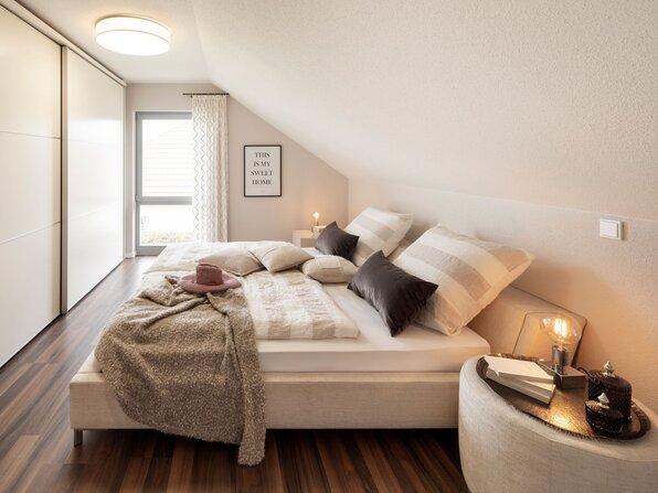 Gemütliches Schlafzimmer im frei geplanten FingerHaus Musterhaus Marburg mit Dachschräge, Doppelbett und modernem Design.
