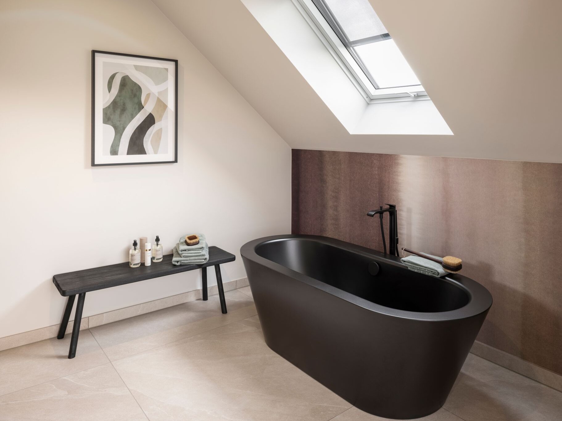Modernes Badezimmer im Dachgeschoss des Musterhauses JUNO 300 in Mülheim-Kärlich mit freistehender schwarzer Badewanne unter Dachschräge.