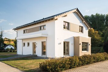 Modernes FingerHaus SENTO 500 Musterhaus in Frankenberg mit Satteldach, hellen Fassaden in Weiß und Holz-Elementen sowie klarer Linienführung.