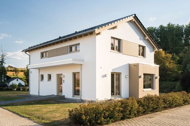 Modernes FingerHaus SENTO 500 Musterhaus in Frankenberg mit Satteldach, hellen Fassaden in Weiß und Holz-Elementen sowie klarer Linienführung.
