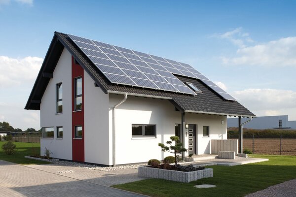 Modernes Einfamilienhaus mit rotem Fassadenelement und großer Photovoltaikanlage auf dem Dach – Musterhaus VIO 400 in Köln.