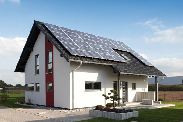 Modernes Einfamilienhaus mit rotem Fassadenelement und großer Photovoltaikanlage auf dem Dach – Musterhaus VIO 400 in Köln.