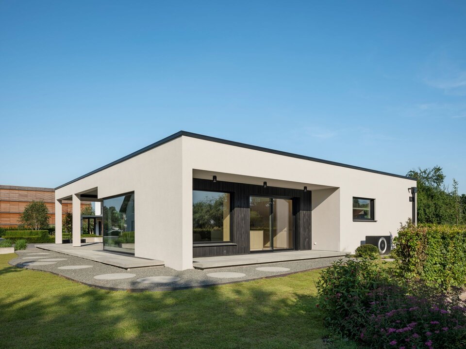 Musterhaus NIVO in Frankenberg mit moderner Bungalowarchitektur, weißer Putzfassade, überdachter Terrasse, großzügigen Fensterflächen und gepflegter Gartenanlage.