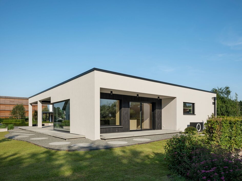 Musterhaus NIVO in Frankenberg mit moderner Bungalowarchitektur, weißer Putzfassade, überdachter Terrasse, großzügigen Fensterflächen und gepflegter Gartenanlage.