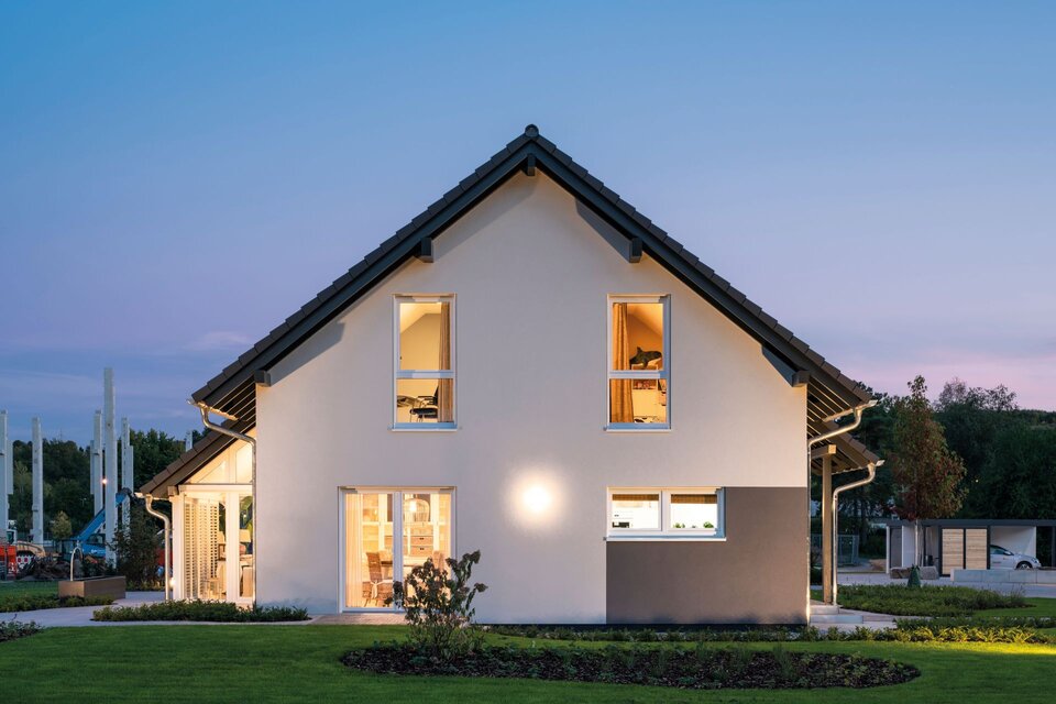 FingerHaus JUNO 402 Musterhaus Frankenberg bei Abendbeleuchtung mit moderner Fassade und Satteldach