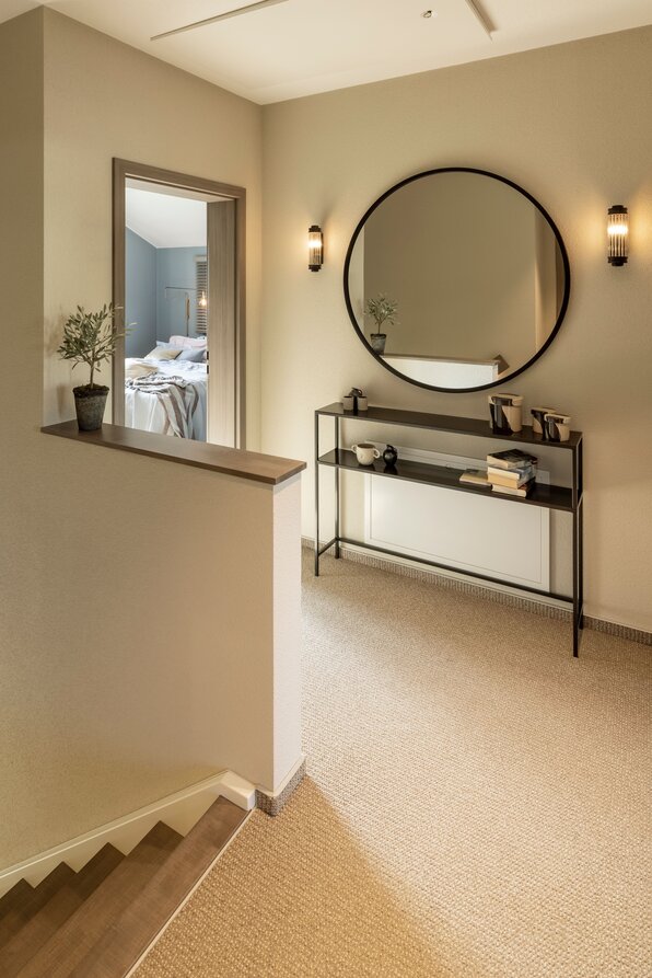 Oberer Flur im FingerHaus ARTIS 300 Musterhaus Würzburg mit rundem Spiegel und eleganter Konsole.