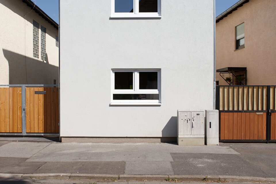 Schmales, mehrstöckiges FingerHaus mit Satteldach und klar strukturierter Fassade in moderner Straßenansicht.