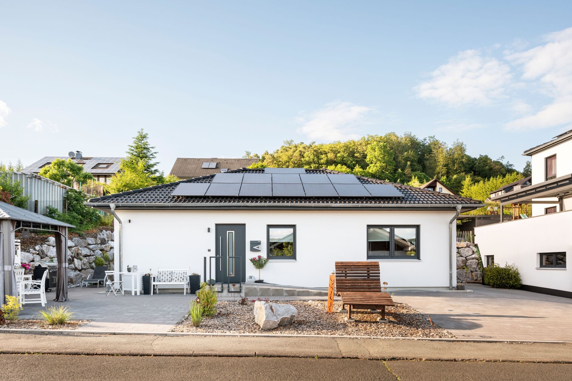 Frontalansicht eines frei geplanten Kundenhauses mit Photovoltaikanlage auf dem Walmdach.