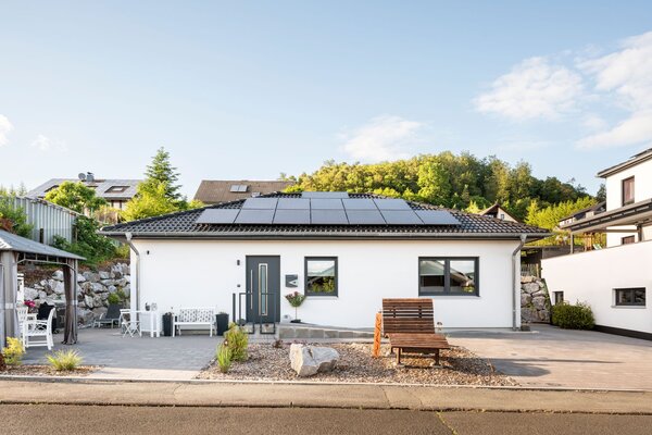 Frontalansicht eines frei geplanten Kundenhauses mit Photovoltaikanlage auf dem Walmdach.
