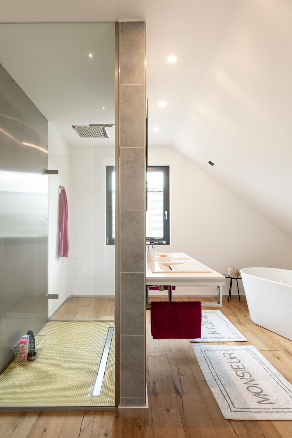 Langes Dachbad mit Dusche, WC und hellem Holzfußboden, modern gestaltet.
