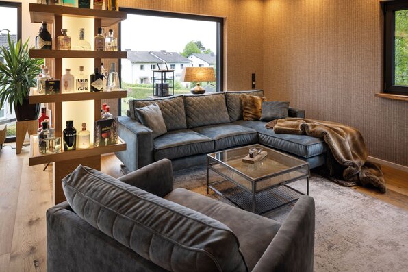 Frei geplantes FingerHaus mit modernem Wohnzimmer, gemütlicher Sitzecke und stilvoller Beleuchtung.