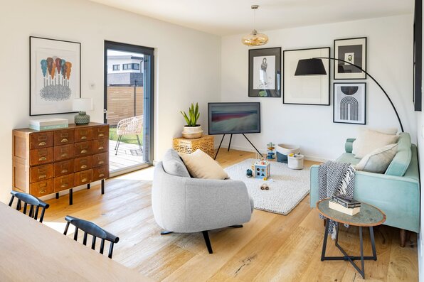 Helles frei geplantes FingerHaus Wohnzimmer mit Parkettboden, moderner Einrichtung und Zugang zur Terrasse.