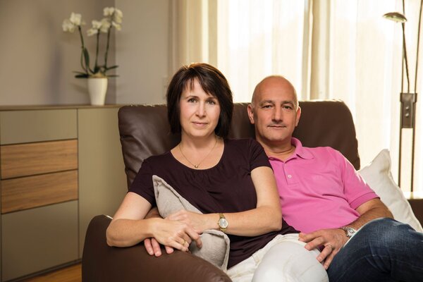 Ein Paar sitzt entspannt auf dem Sofa in ihrem gemütlich eingerichteten Wohnzimmer eines frei geplanten FingerHaus.