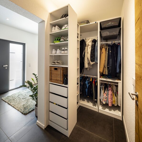 Eingangsbereich mit offener Garderobe, Regalsystem mit Schuhen und Körben sowie Kleiderstangen für Jacken und Kindersachen.