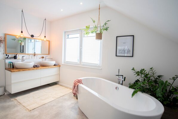 Modernes Badezimmer in einem frei geplanten FingerHaus mit freistehender Badewanne, Doppelwaschbecken und Pflanzen.