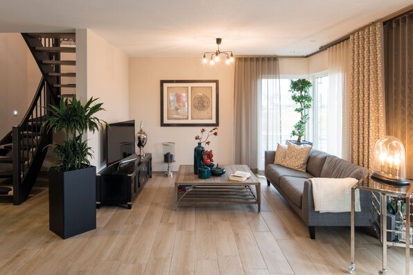 Wohnzimmer im FingerHaus MEDLEY 300 B Musterhaus Berlin/Werder mit grauem Sofa, modernem Couchtisch und stilvoller Dekoration.