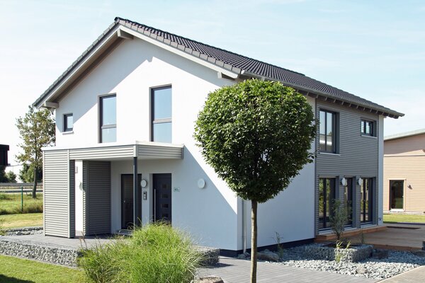 Außenansicht des FingerHaus Musterhauses NEO 300 in Hannover mit moderner weiß-grauer Fassade, Satteldach und gestalteter Einfahrt.