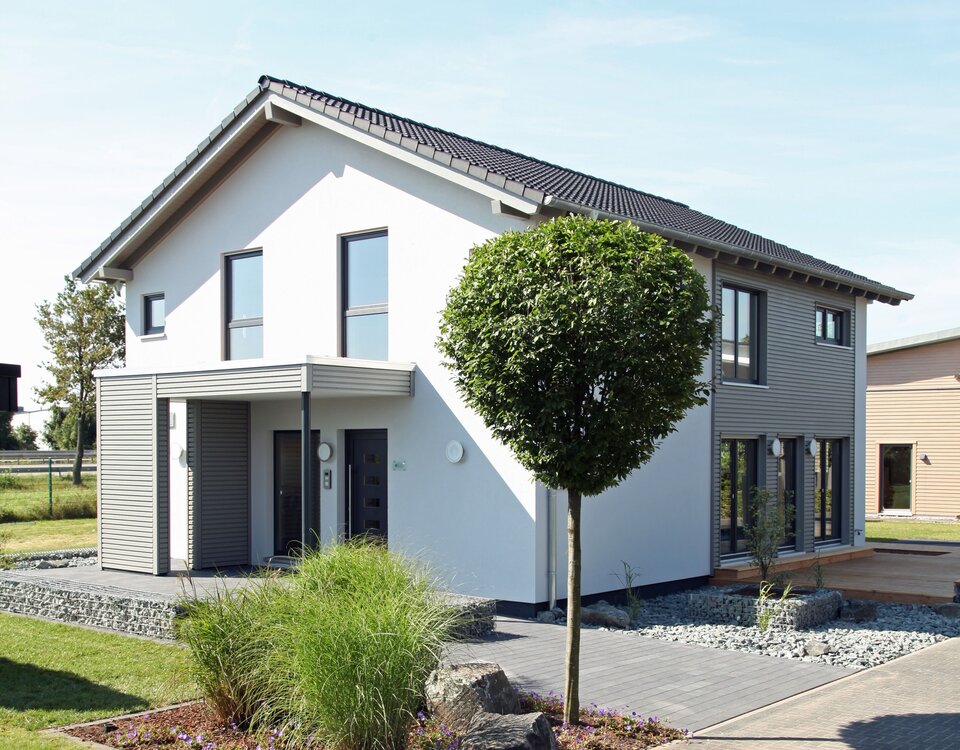 Außenansicht des FingerHaus Musterhauses NEO 300 in Hannover mit moderner weiß-grauer Fassade, Satteldach und gestalteter Einfahrt.