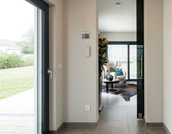 Flur der Einliegerwohnung im Musterhaus ALTERO in Gießen mit großformatigen Bodenfliesen, Blick in den Büroraum und Zugang zum Außenbereich  