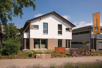 Straßenansicht des Musterhauses MEDLEY in Fellbach mit moderner Holzfassade, klarer Linienführung und großer Fensterfront.