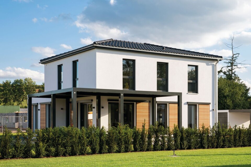 Modernes FingerHaus MEDLEY 300 B Musterhaus in Frankenberg mit Flachdach-Erker, großer überdachter Terrasse und klarer Architektur in Weiß mit Holzelementen.