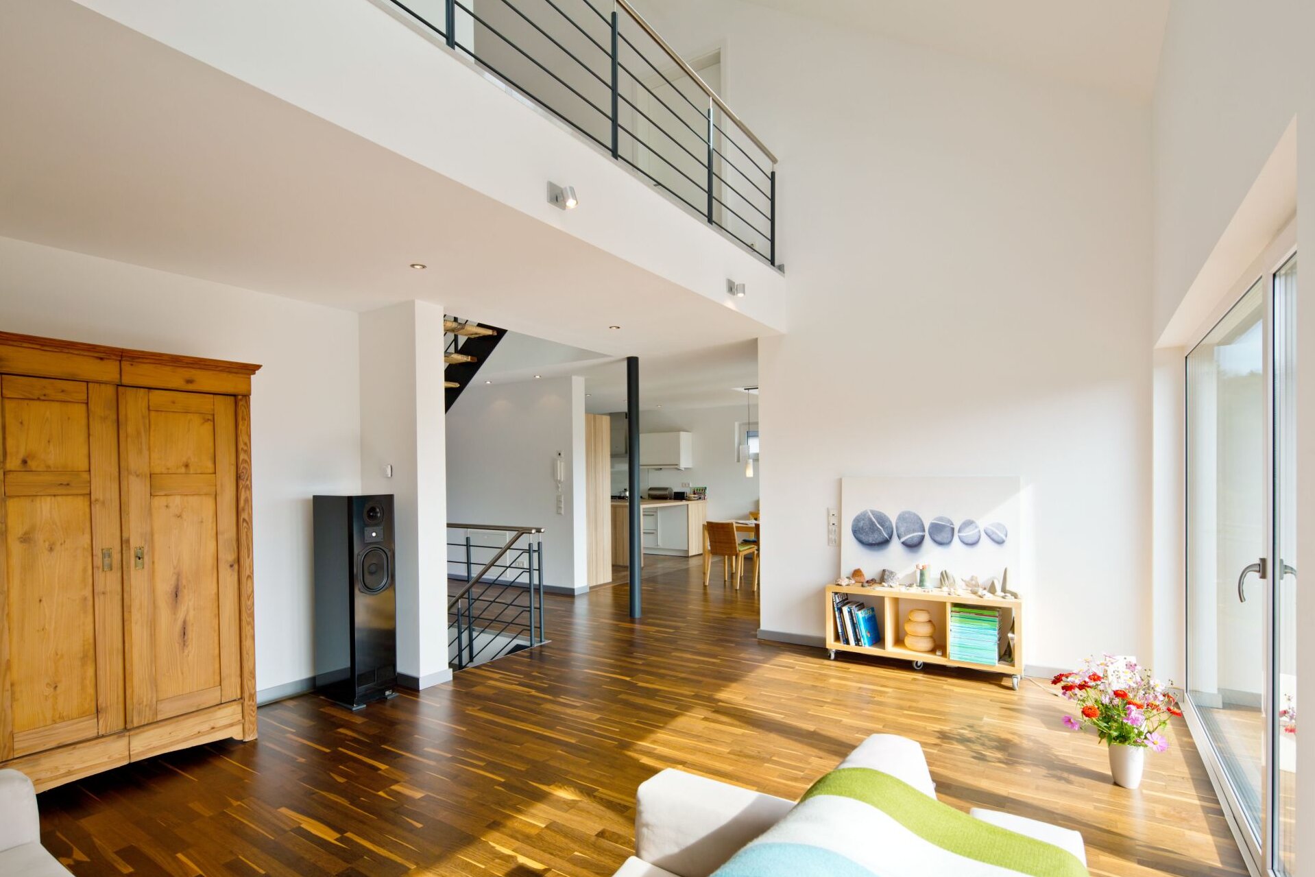 Modernes Wohnzimmer in einem frei geplanten FingerHaus mit Galerie, großen Fensterflächen, Holzfußboden und hellem Interieur.