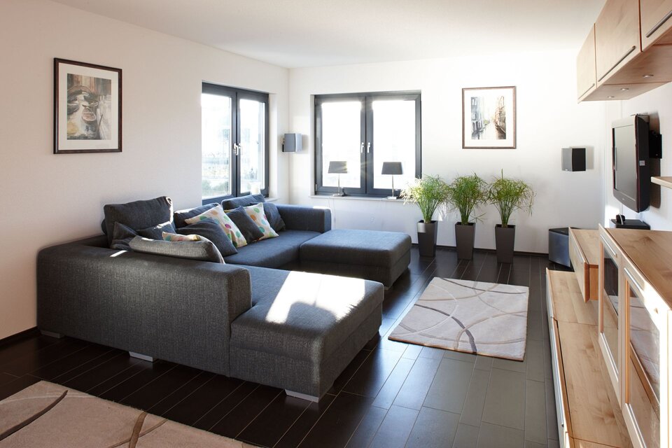 Helles Wohnzimmer mit großer Eckcouch, modernen Bildern und viel Tageslicht.