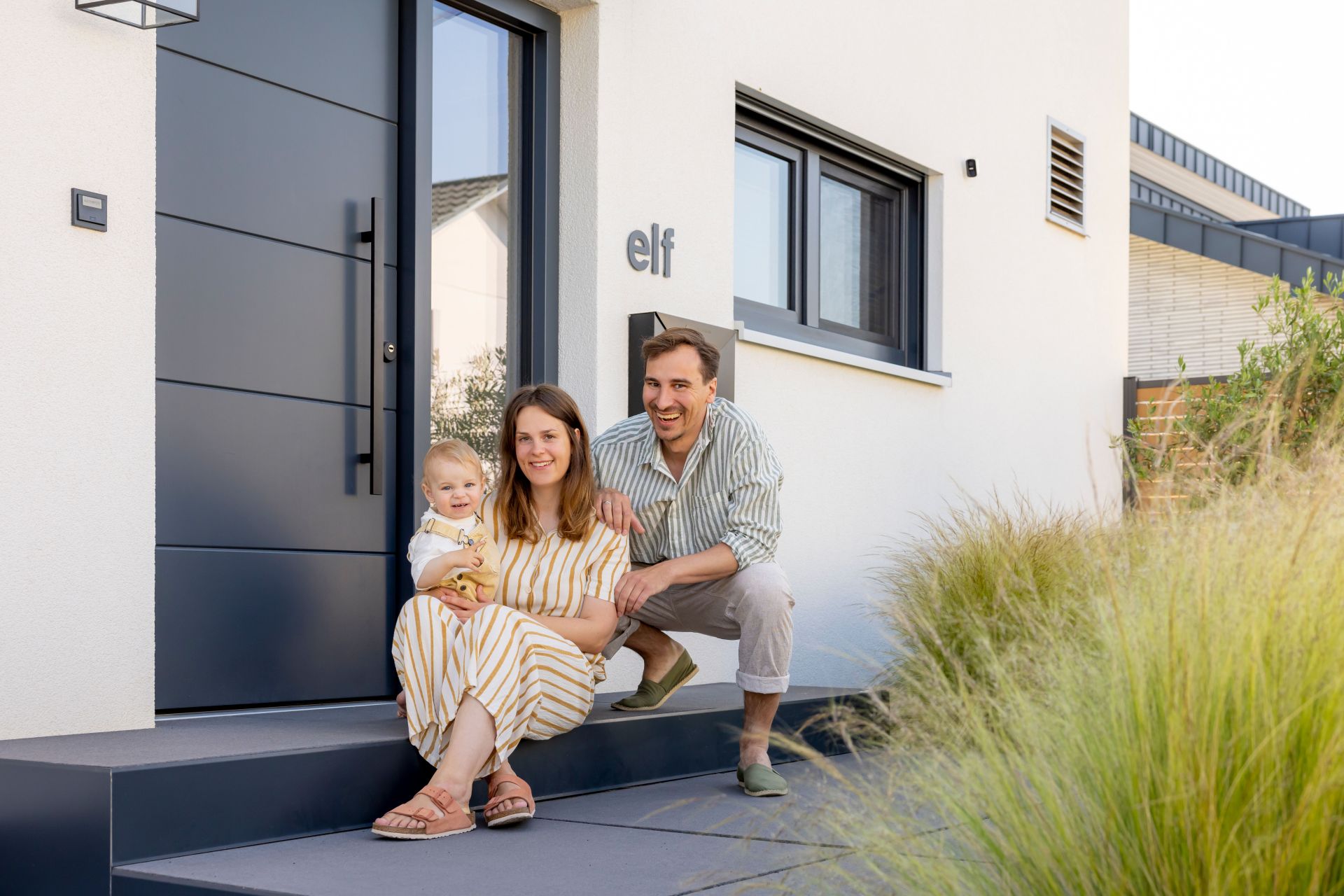 Frei geplantes FingerHaus mit modernem Eingangsbereich und Familie davor.