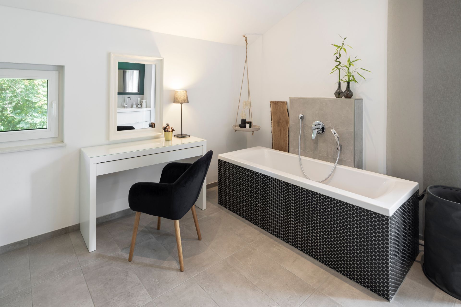 Modernes Badezimmer in einem frei geplanten FingerHaus mit Badewanne in schwarzer Mosaikverkleidung, Schminktisch und eleganter Beleuchtung.
