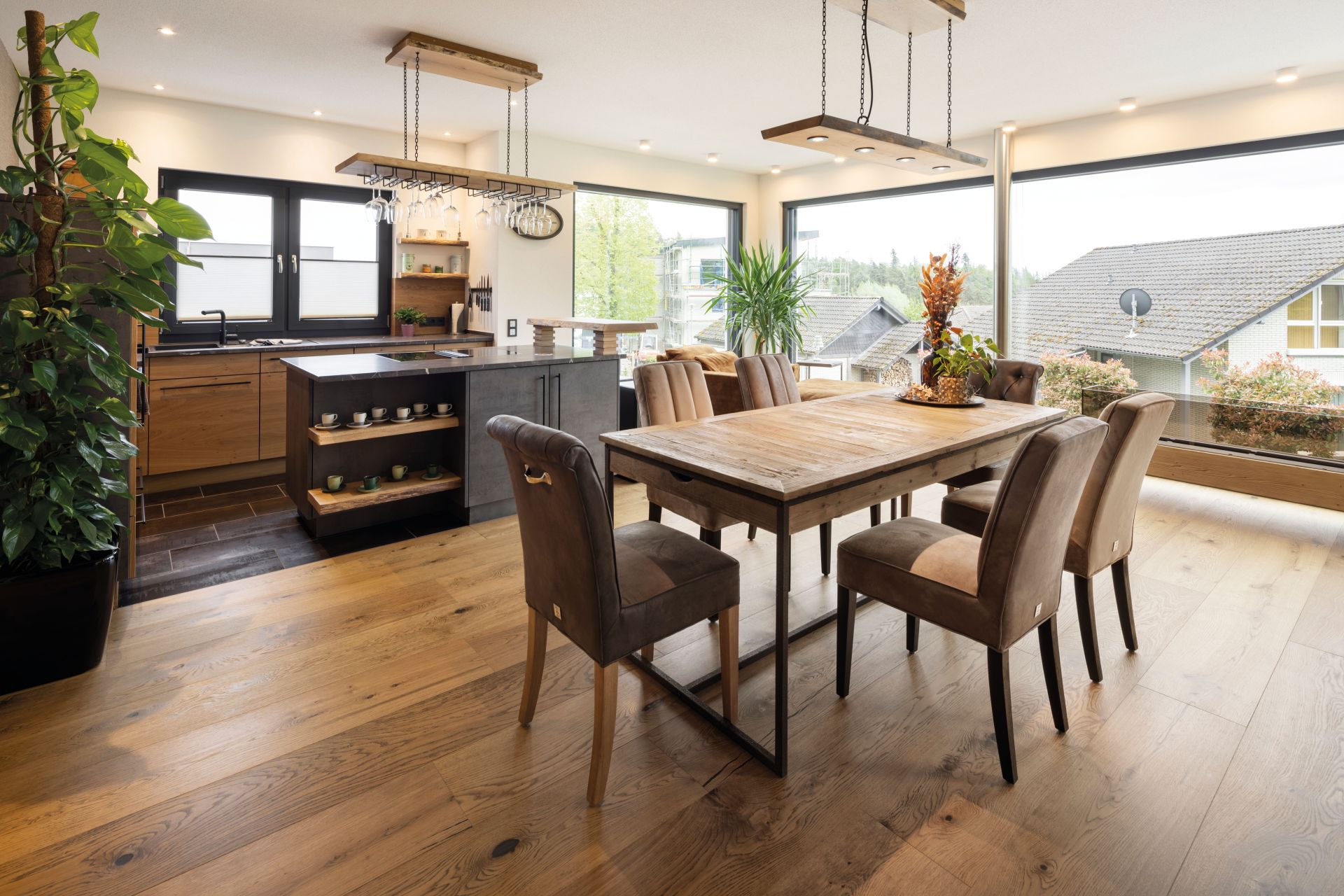 Offener Wohn- und Essbereich mit moderner Küche, großem Holztisch und bodentiefen Fenstern in einem frei geplanten Finger-Haus.