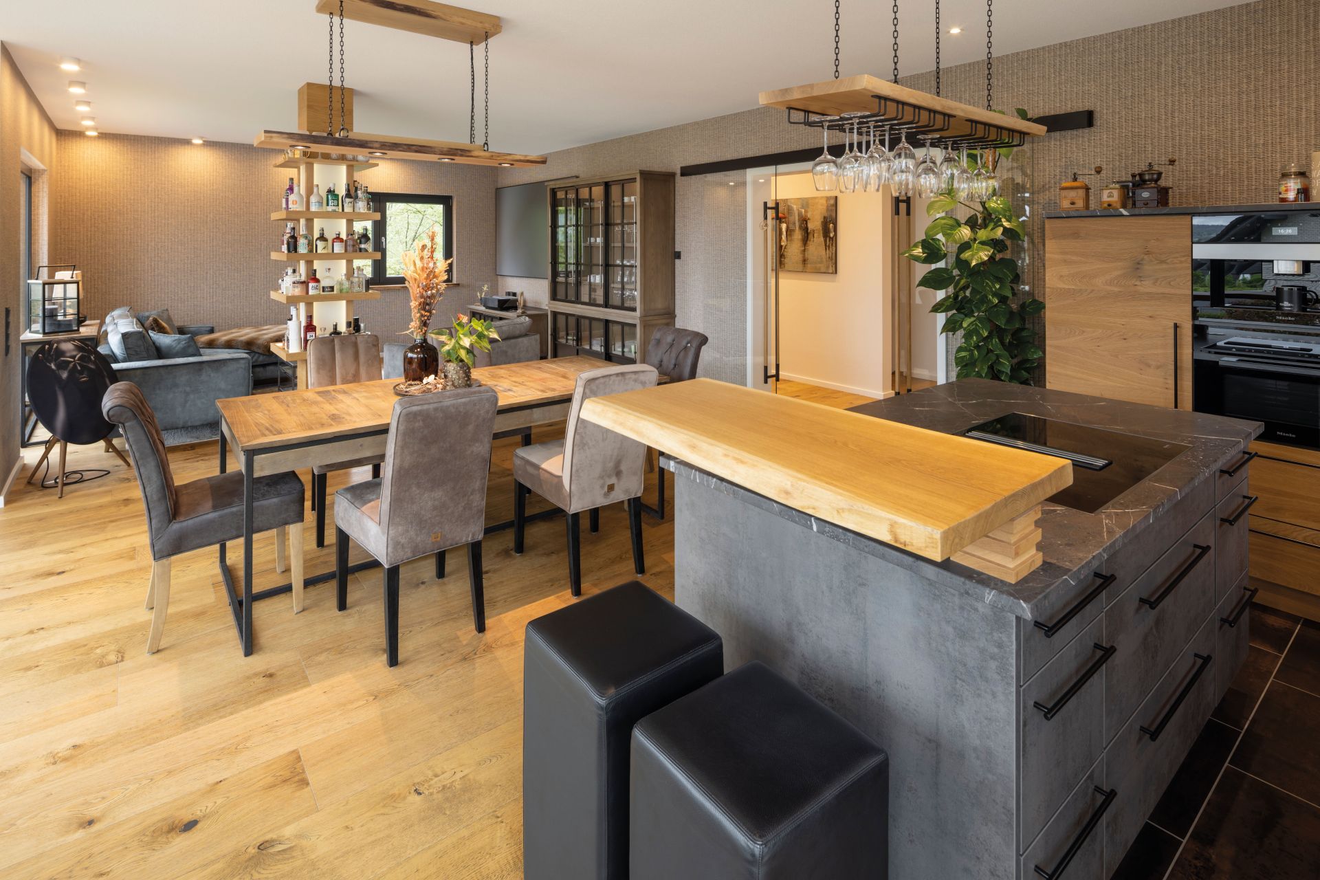 Moderne offene Wohnküche mit Kochinsel, Barbereich und großem Esstisch, kombiniert mit stilvollem Wohnbereich.