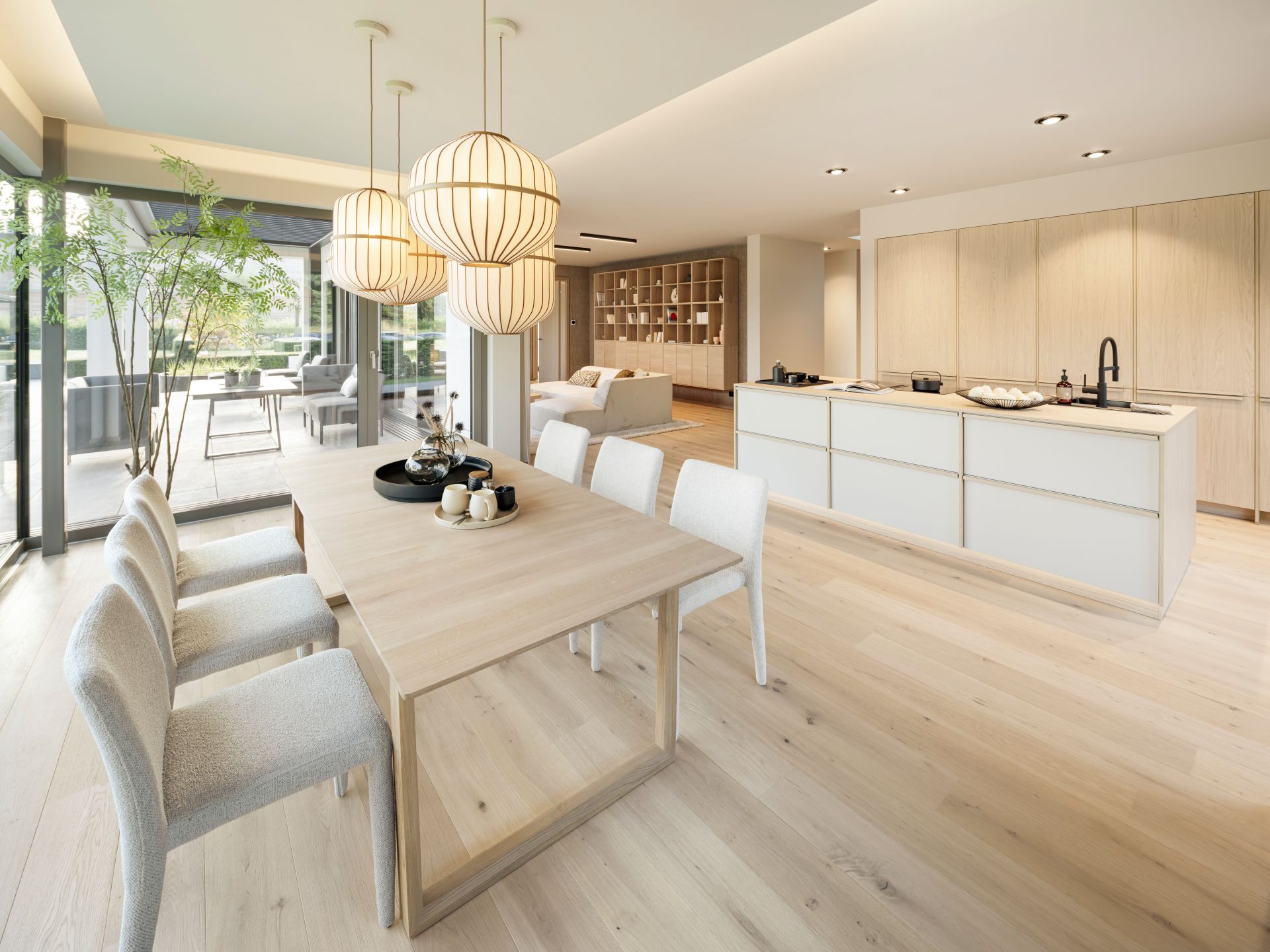 Offener Ess-, Koch- und Wohnbereich im FingerHaus Musterhaus NIVO in Frankenberg mit Holztisch, Kücheninsel und großen Glasflächen.