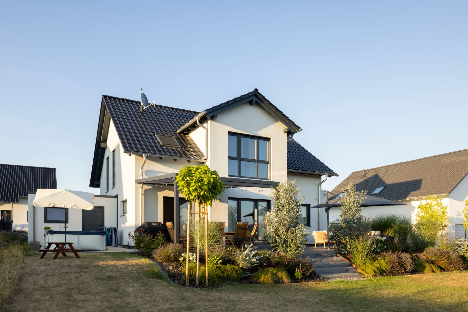 Außenansicht eines Einfamilienhauses SENTO 403 mit Satteldach, Terrassenüberdachung und Gartenanlage
