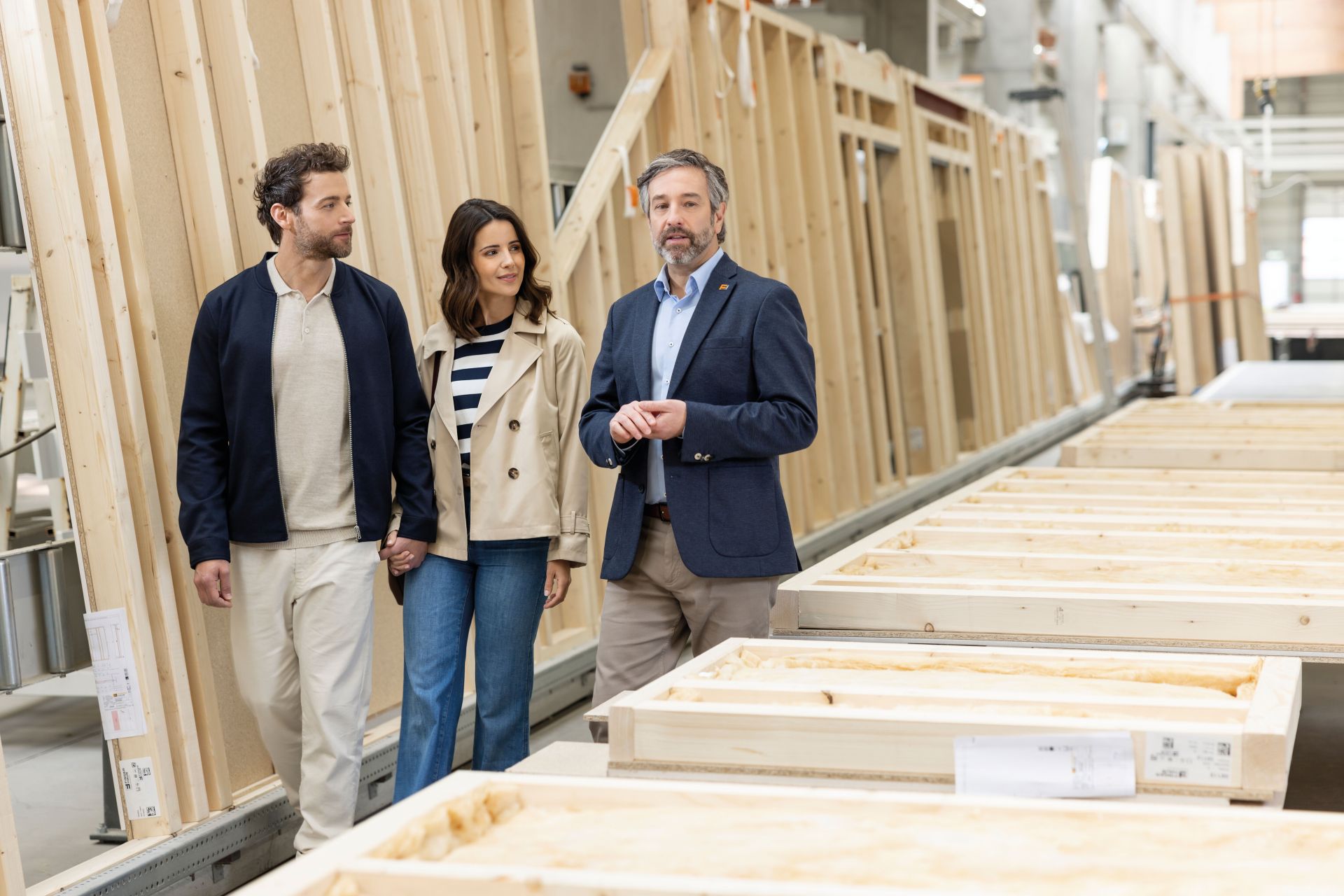 Werksbesichtigung bei FingerHaus: Ein Paar wird von einem Mitarbeiter durch die Produktion geführt, wo vorgefertigte Holzrahmenwände für Fertighäuser entstehen.
