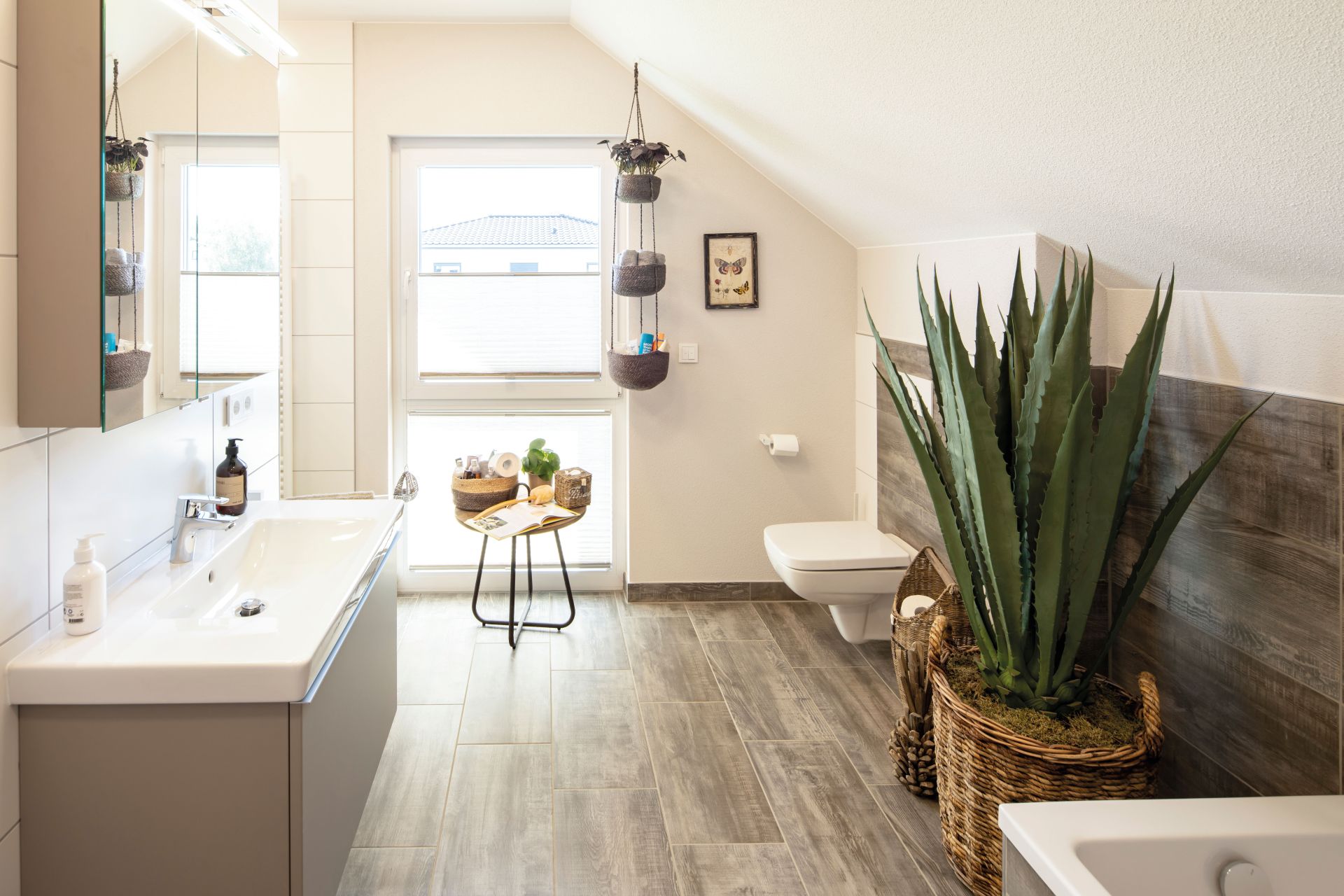 FingerHaus JUNO 402 Musterhaus Frankenberg – modernes Badezimmer mit Dachschräge, großem Fenster und stilvollen Details