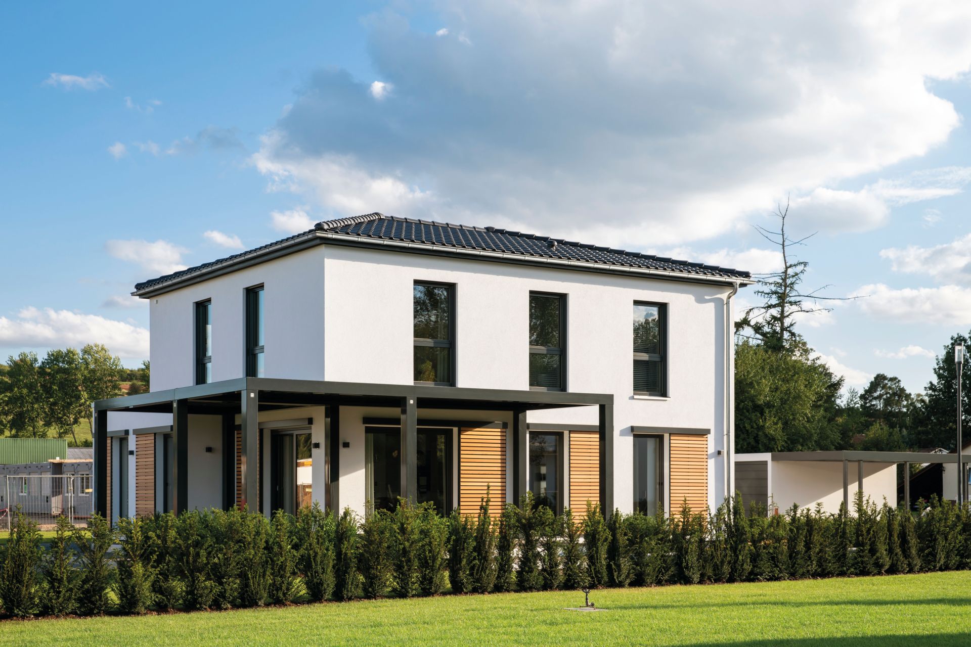 Modernes FingerHaus MEDLEY 300 B Musterhaus in Frankenberg mit Flachdach-Erker, großer überdachter Terrasse und klarer Architektur in Weiß mit Holzelementen.