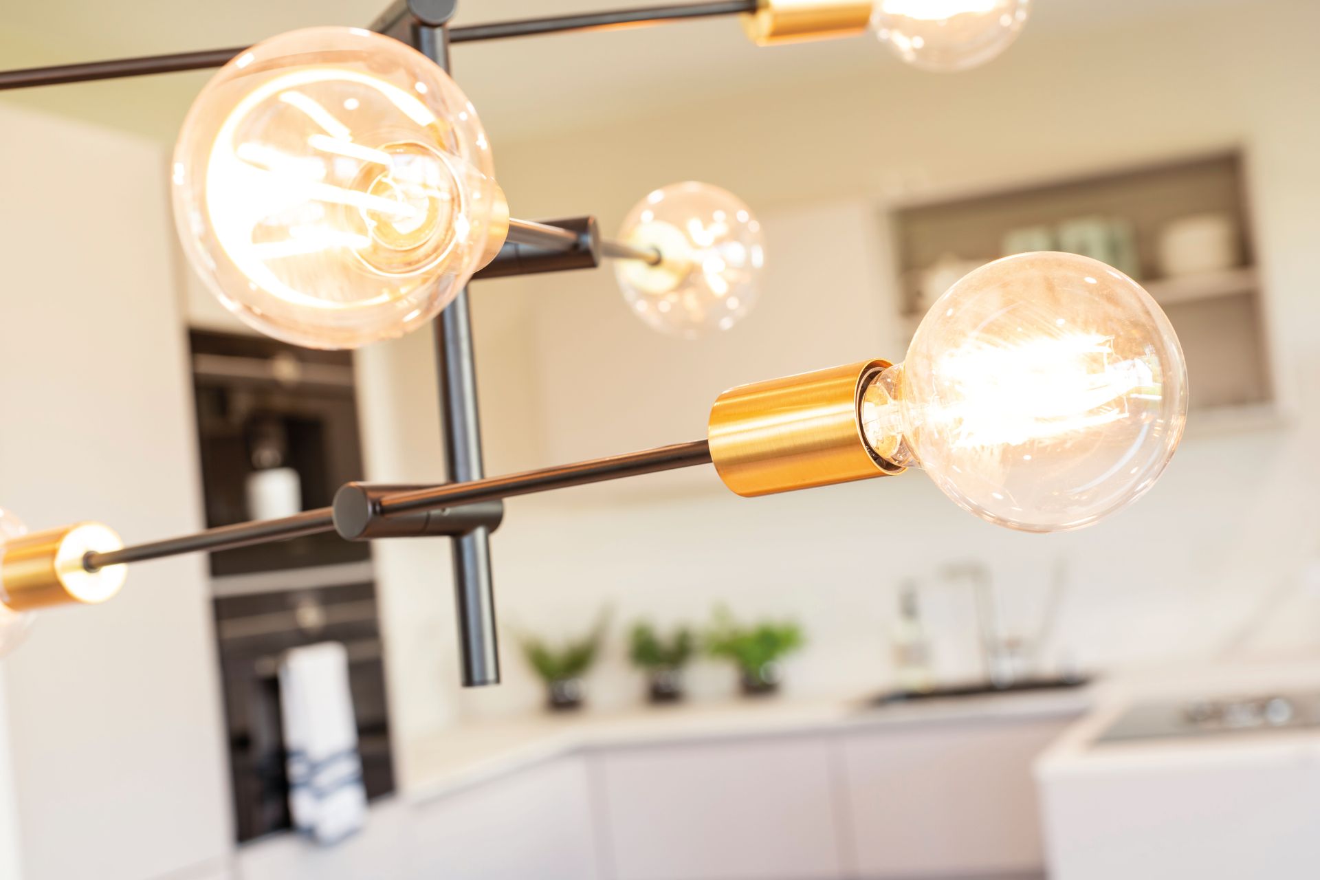 Detailaufnahme einer modernen Pendelleuchte mit goldfarbenen Fassungen im Essbereich des Musterhauses MEDLEY 300 B in Frankenberg.