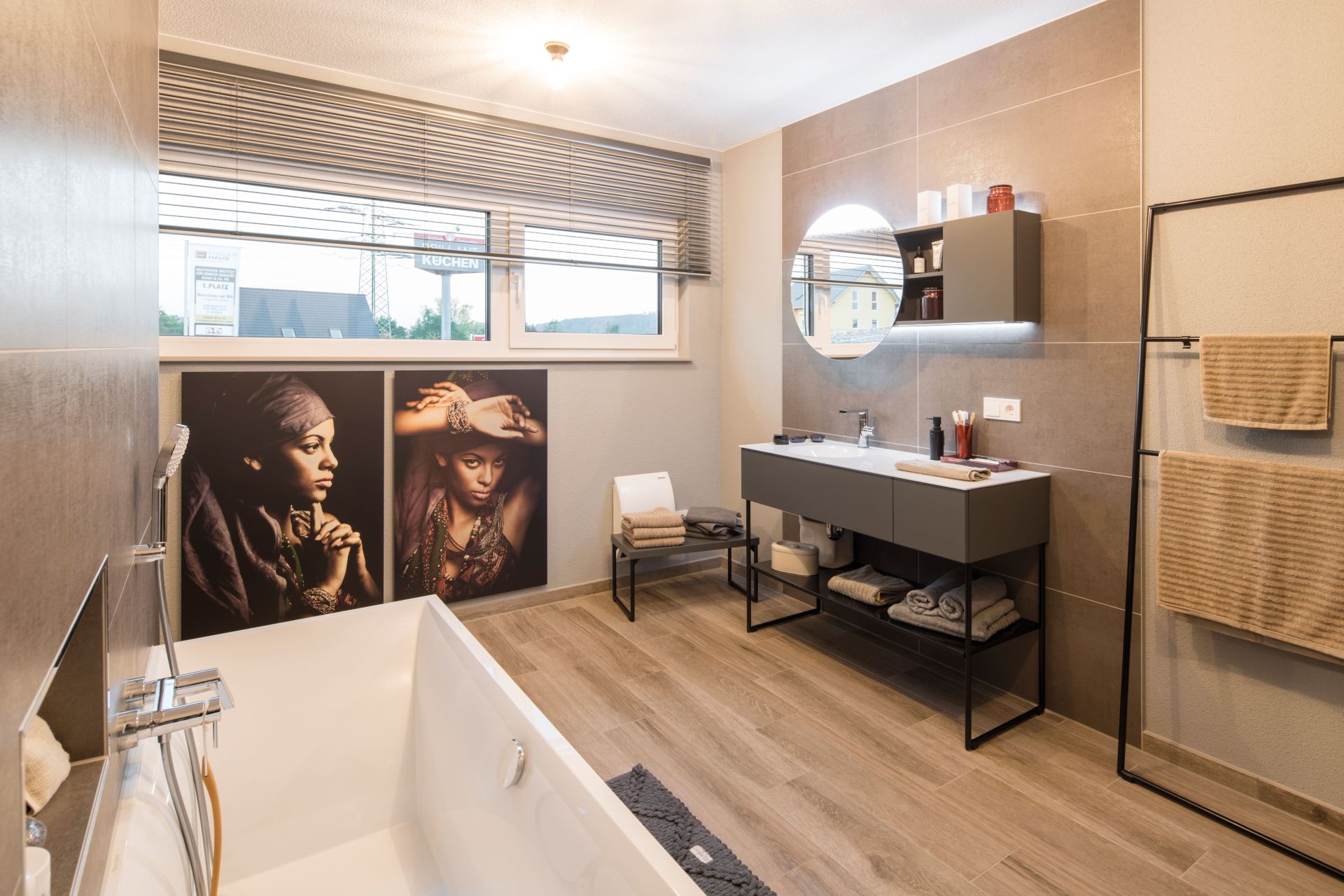 Modernes Badezimmer im Musterhaus MEDLEY 300 B in Kassel mit freistehender Badewanne, stilvollem Waschtisch und dekorativen Wandbildern.