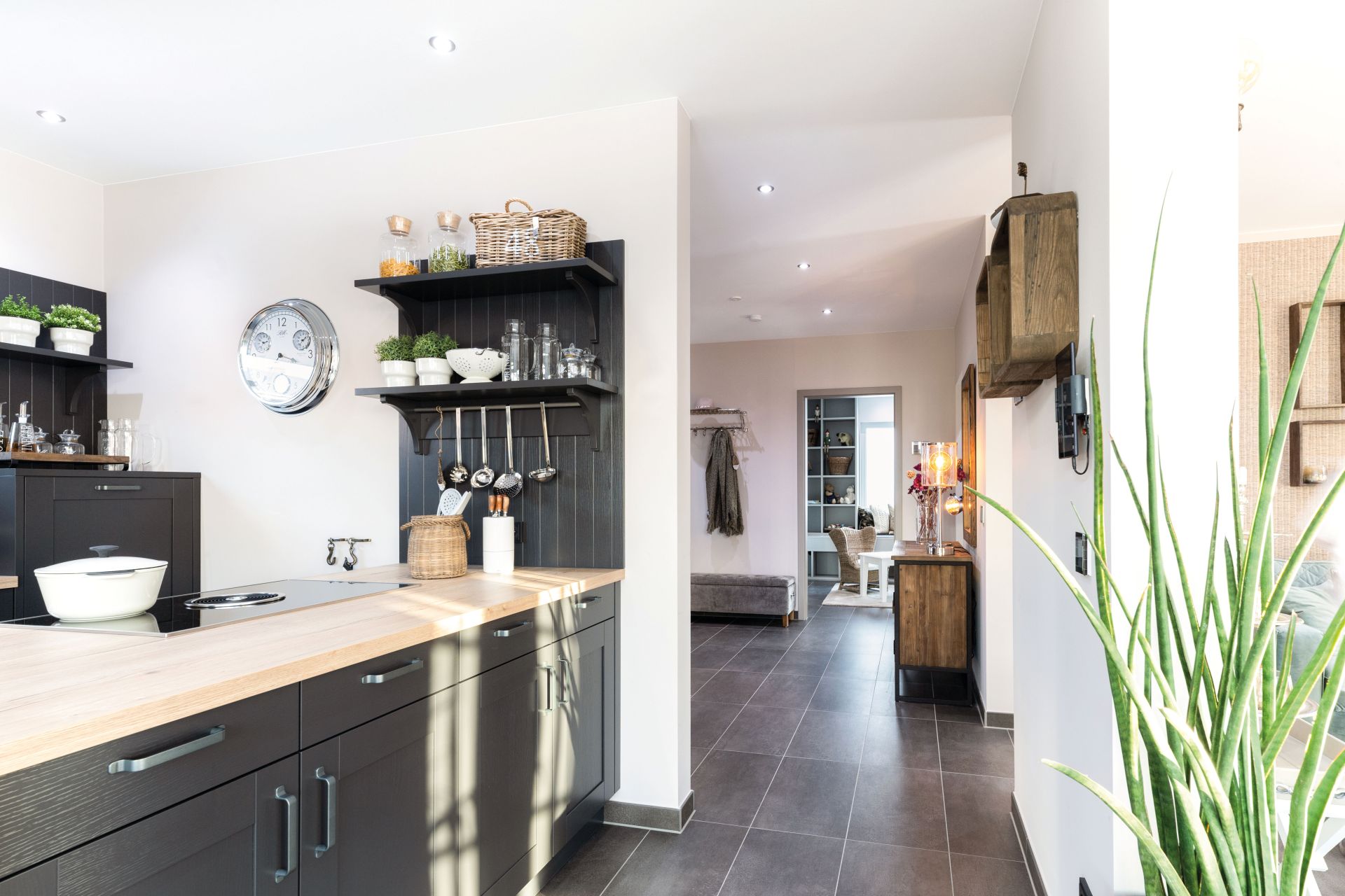 Stilvolle Küche mit dunklen Fronten, Holzarbeitsplatte und offenen Regalen im Musterhaus MEDLEY 300 B in München/Poing.