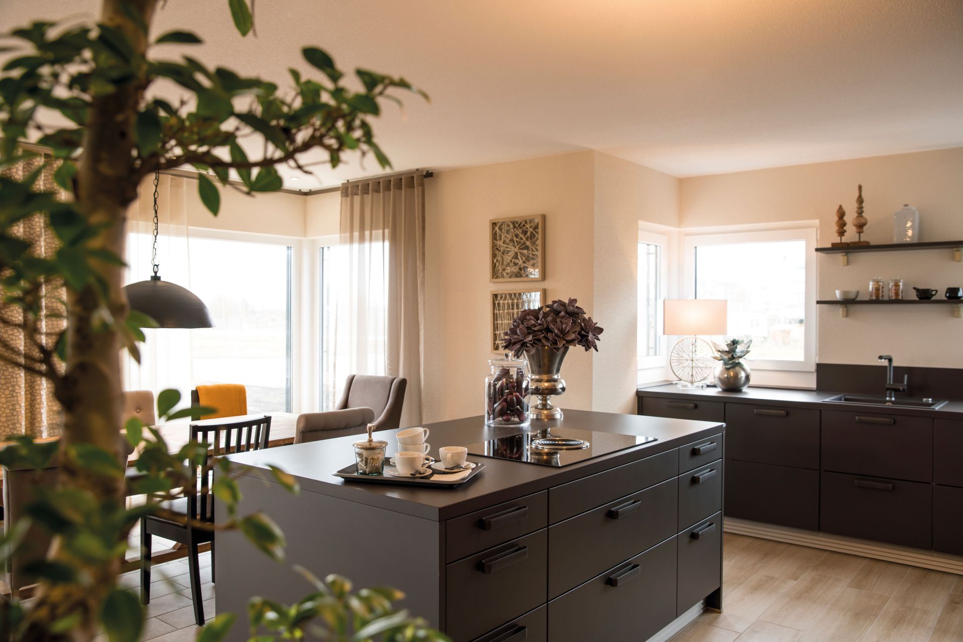 Moderne Küche mit Kochinsel im FingerHaus MEDLEY 300 B Musterhaus Berlin/Werder, angrenzend an Ess- und Wohnbereich.