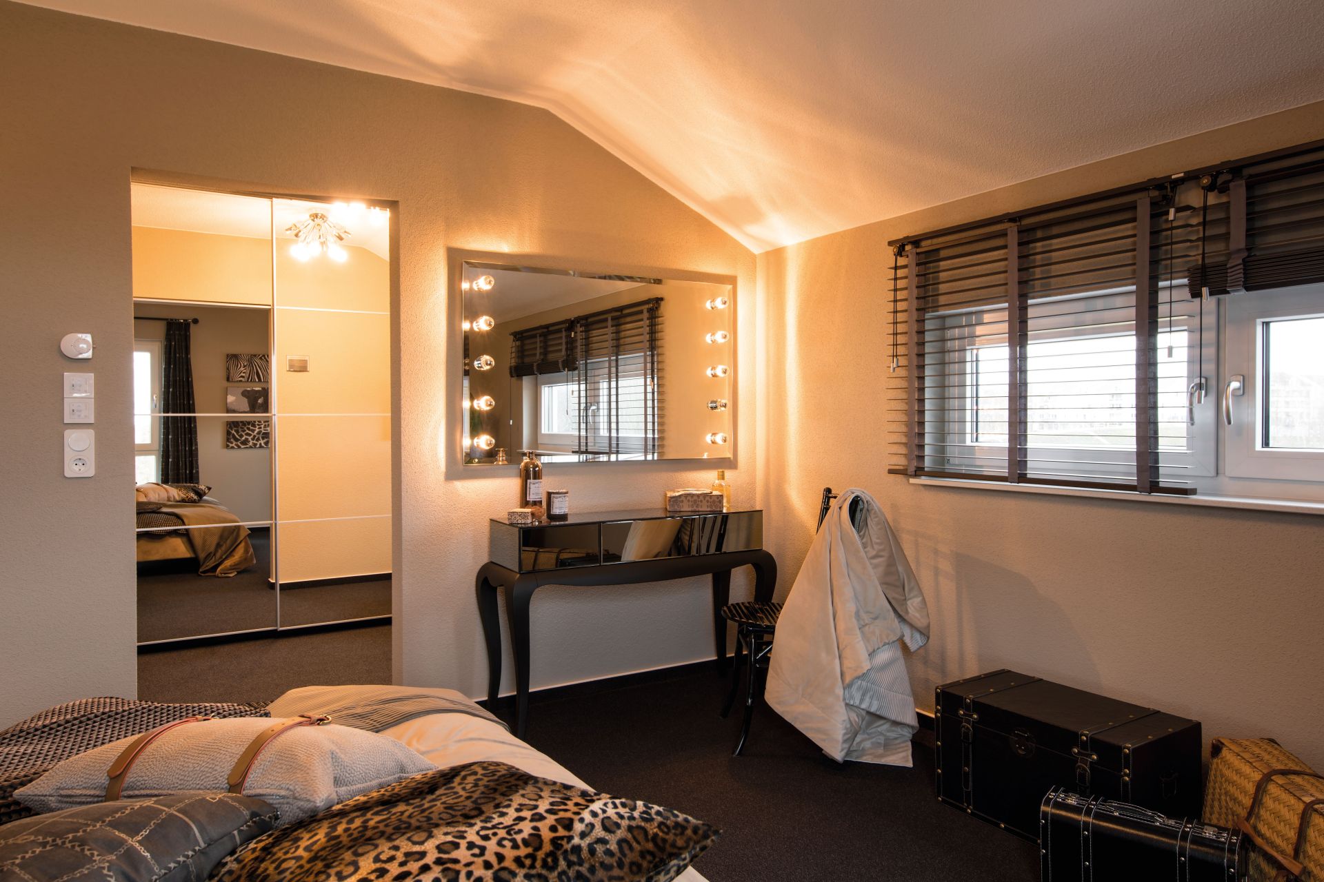 Schlafzimmer im FingerHaus MEDLEY 300 B Musterhaus Berlin/Werder mit gemütlicher Einrichtung, Schminktisch mit Spiegelbeleuchtung und modernen Details.