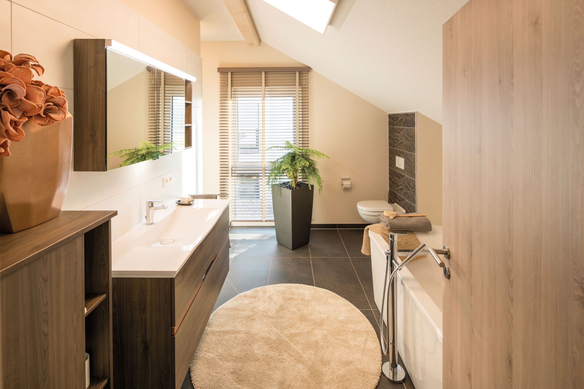 Modernes Badezimmer im FingerHaus NEO Musterhaus Günzburg mit Badewanne, Doppelwaschtisch und eleganter Holzoptik.
